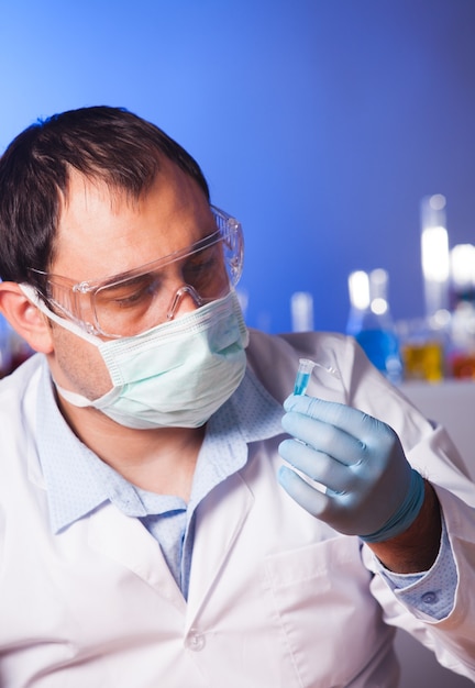 과학자는 연구에 대해 생각하고 eppendorf 튜브를 들고 있습니다.