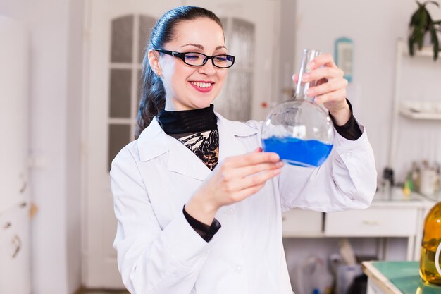 A scientist in a laboratory studying the liquid in the beaker