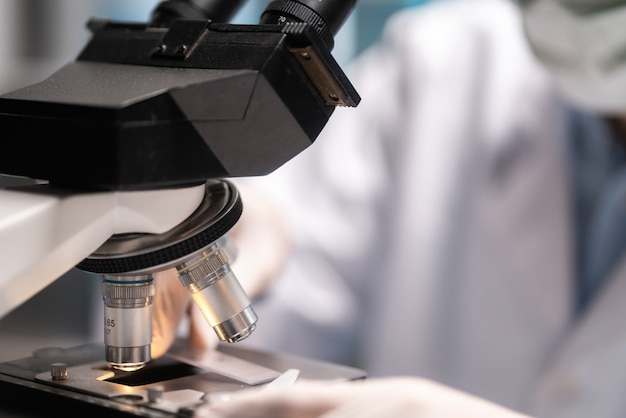 Scientist looking through scientific microscope lense in laboratory, scientist doing research in term of medicine biotechnology biology or chemistry, doctor analyzing work in medical microbiology lab