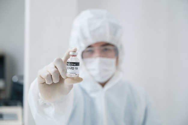 사진 실험실에서 covid-19, 코로나바이러스에 대한 효과적인 백신 병을 보여주는 의료 보호 ppe의 과학자 남자