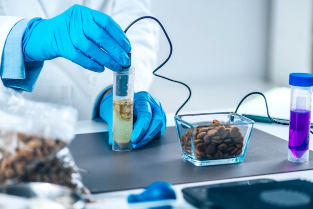Scientist measuring ph of dissolved pet food in sample tube with ph meter