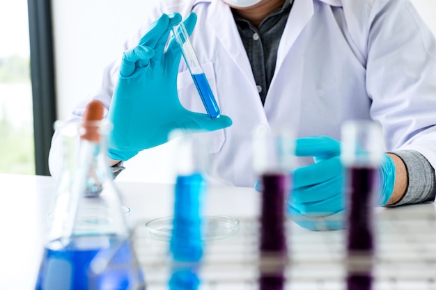 Scientist or medical in lab coat holding test tube with reagent 