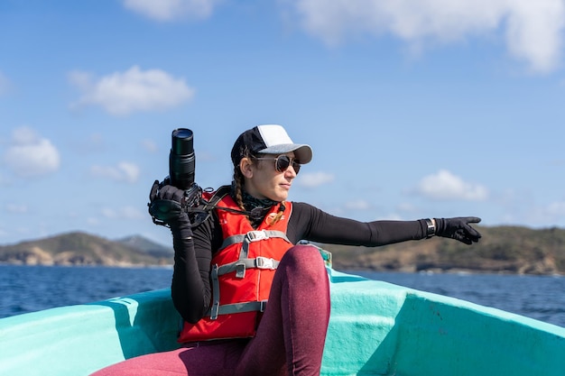 Scientist pointing to the sea carrying a camera on boat