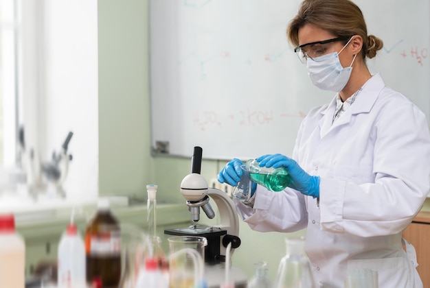 Scientist pouring substance from into Erlenmeyer flask in a laboratory during research work.