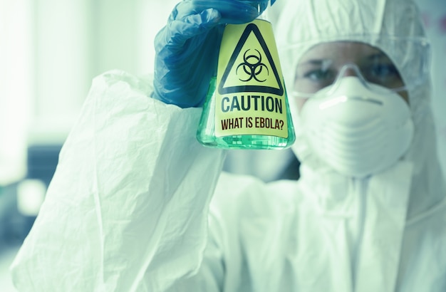 Photo scientist in protective suit holding beaker