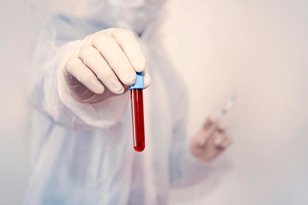 Ученый в защитном костюме держит в руке пробирку с кровью. Скопируйте пространство. лаборант делает анализы крови. разработка вакцины против болезни и вирусной концепции
