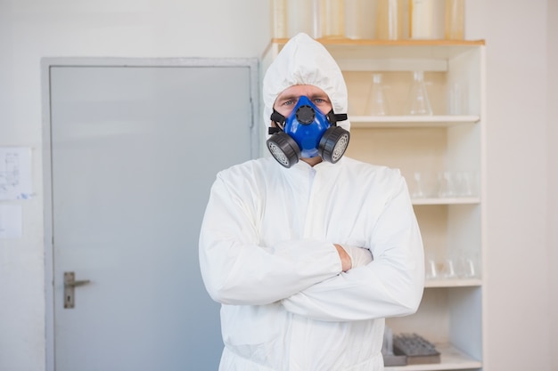 Scientist in protective suit looking at camera with arms crossed 