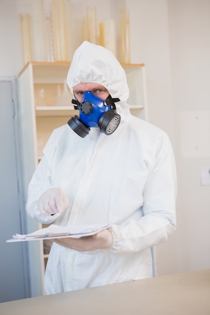 Scientist in protective suit pointing clipboard 