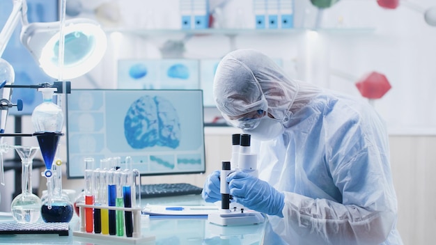 Scientist researcher doctor analyzing blood slide using medical microscope developing vaccine against coronavirus during biochemistry experiment in hospital laboratory. Medicine concept