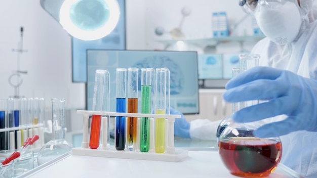病院の実験室での微生物学実験中に液体溶液を混合する医療用透明ガラスを使用する科学者研究者医師。 covid19に対するワクチンを開発している微生物学者の男性