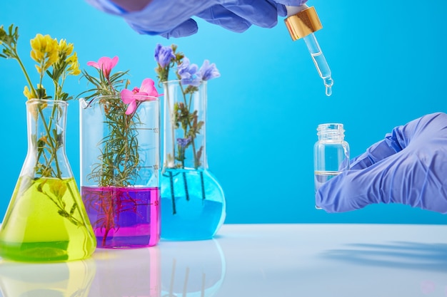 The scientist's hands hold a bottle of cosmetics, test tubes with plants in the background.