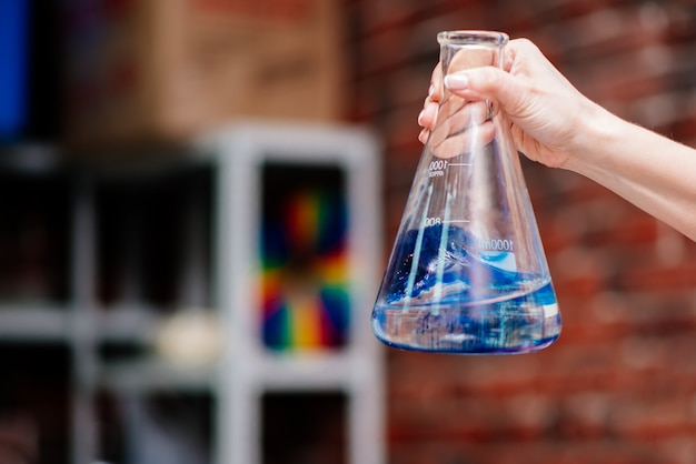 Foto lo scienziato mostra come gli elementi chimici reagiscono in un pallone con vitalità blu