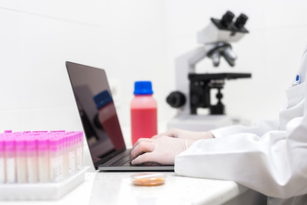scientist using laptop in laboratory. close-up partial view of scientist using laptop in laboratory.