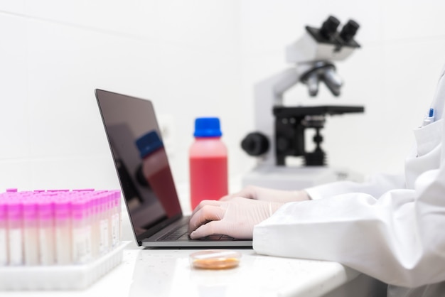 scientist using laptop in laboratory. Close-up partial view of scientist using laptop in laboratory.