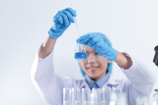 Scientist with equipment and science experiments, laboratory glassware containing chemical liquid for research or analyzing a sample into test tube in laboratory.