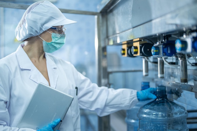 Photo scientist worker checking the quality of water bottles on the machine conveyor line at factory