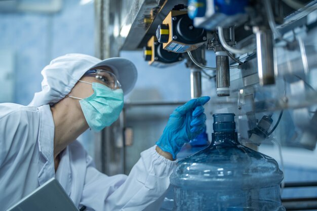 Photo scientist worker checking the quality of water bottles on the machine conveyor line at factory