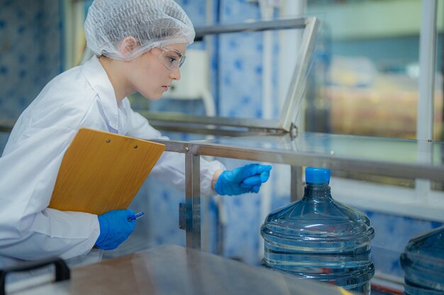 Photo scientist worker checking the quality of water bottles on the machine conveyor line at the industria