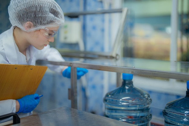 Photo scientist worker checking the quality of water bottles on the machine conveyor line at the industria