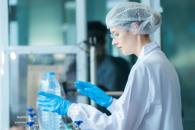 Photo scientist workers checking the quality of water bottles on the machine conveyor line