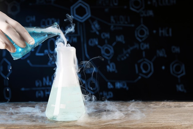 Scientist working with laboratory glassware and space for text at wooden table closeup Chemical reaction