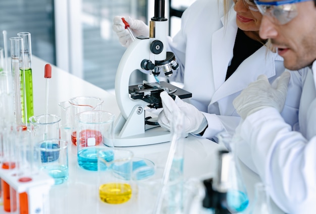 Scientists checking medical liquid with microscope while doing health care research in laboratory