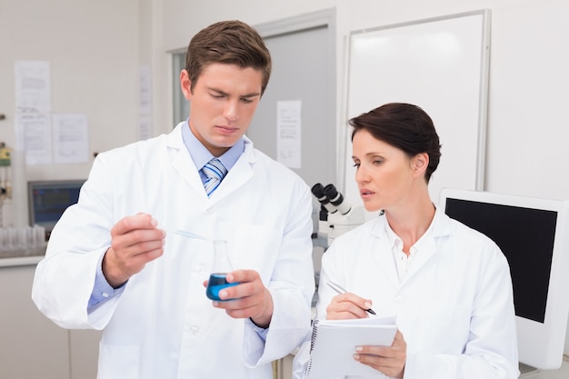 Scientists examining attentively pipette with blue fluid