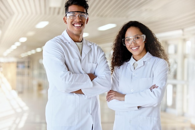 Ученые будущего Обрезанный портрет двух молодых студентов-естественников, стоящих со скрещенными руками в коридоре кампуса