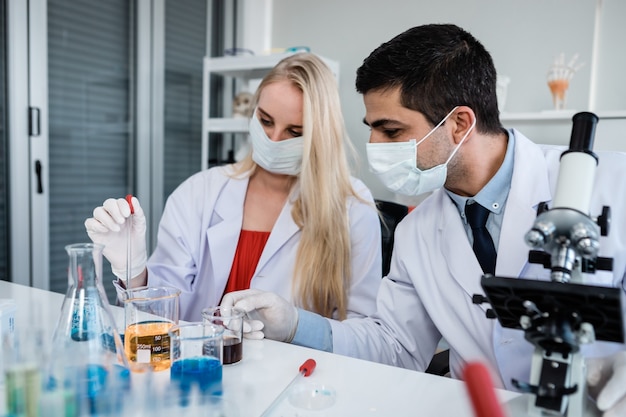 Scienziati che guardano la provetta con il campione in uno scienziato di laboratorio di chimica o una giovane donna