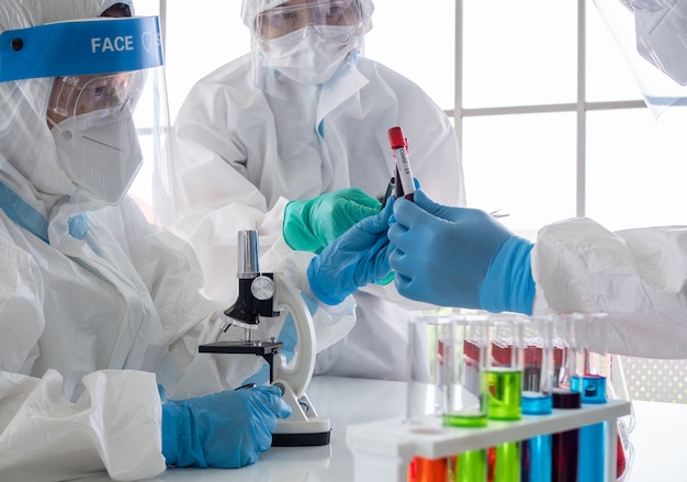 Photo scientists and microbiologists hold test tubes with blood collected from patients