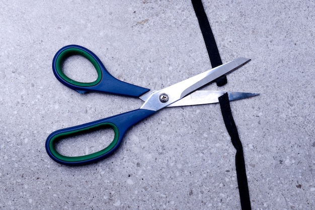 Scissor cutting the black ribbon on the table