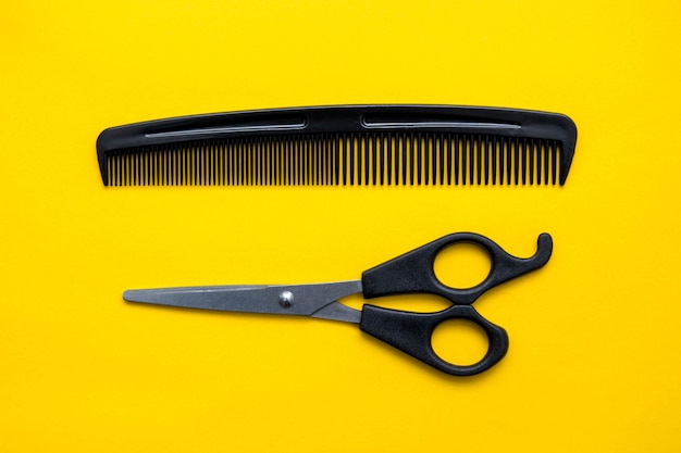 Scissors and comb for hairdresser on a yellow background. Top view. Copy, empty space for text