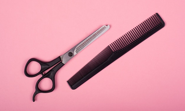 Photo scissors and comb on a pink background