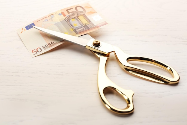 Ножницы режут банкноту евро на столе