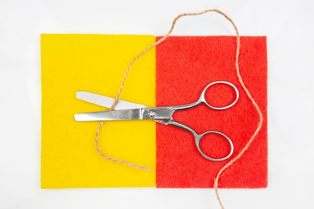Scissors for cutting and rope on a colored background