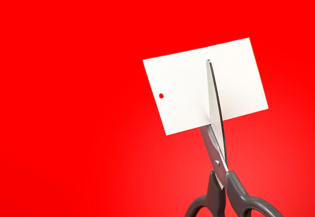 scissors cutting a tag on a red background close up