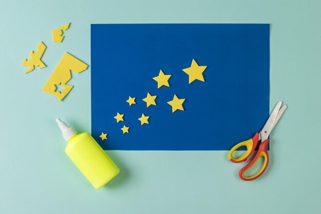 Scissors glue and applique of yellow stars on a blue background