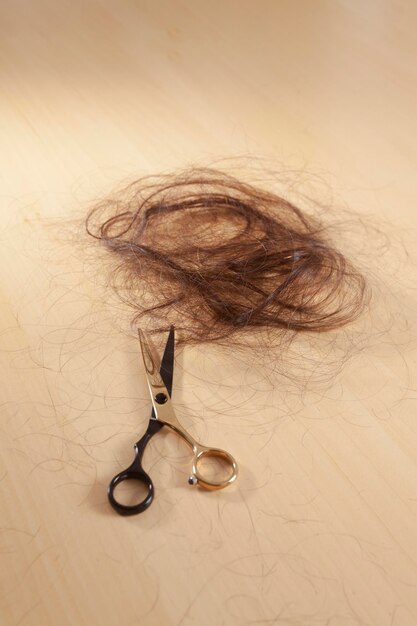 Scissors and hair sitting on a wooden surface and next to it