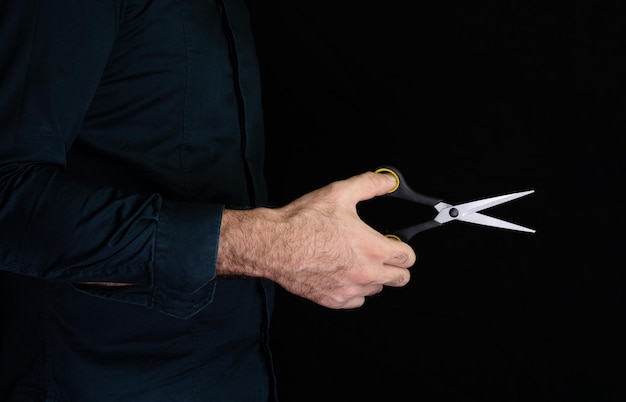 Scissors in hand on black background