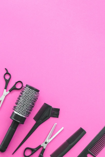 Scissors and other hairdresser's accessories on pink background flat lay Space for text