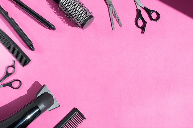 Photo scissors and other hairdressers accessories on pink background flat lay space for text