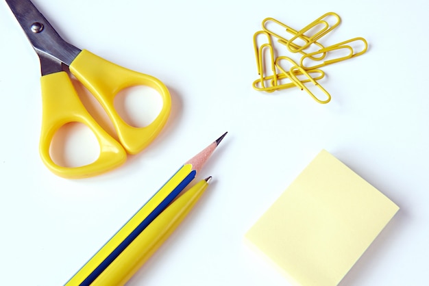 Scissors, pencil, pen, paper clips, paper for notes on a white surface