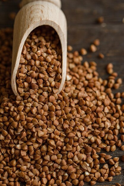 Scoop and buckwheat macro view on rustic background Close up raw buckwheat background