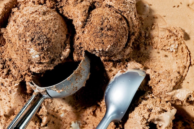 A scoop of chocolate ice cream with a spoon next to it.