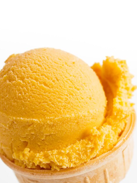 Scoop of gourmet pumpkin gelato in cake cone on white background.