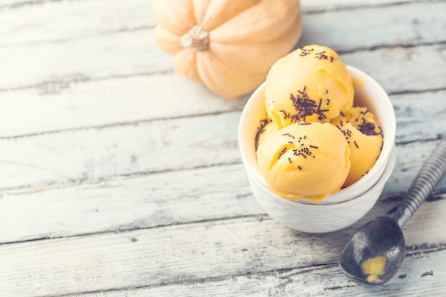 Scoop of gourmet pumpkin ice cream gelato in white bowl over wooden