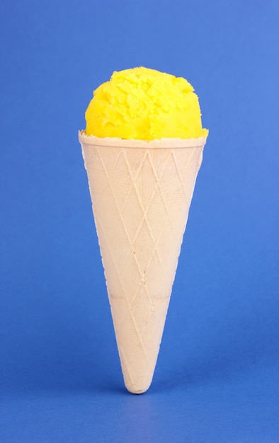 Совок лимонного мороженого в вафельном рожке на синем фоне