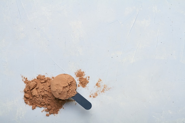 A scoop of protein powder on grey background