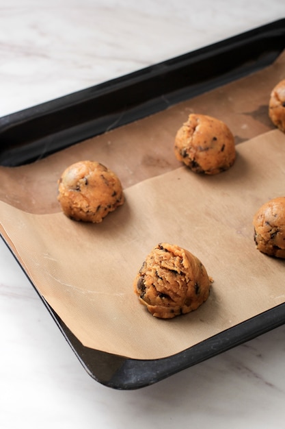 Scooped Raw Chocolate Chips Cookies Mixture on the Baking Tray with Parchment Paper,  Ready to Bake