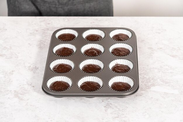 Scooping chocolate cupcake dough into the cupcake liners